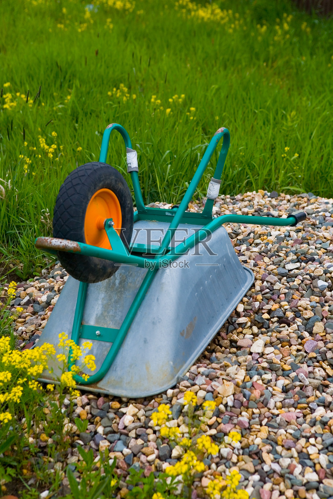 倒立的建筑手推车躺在一堆瓦砾上。照片摄影图片