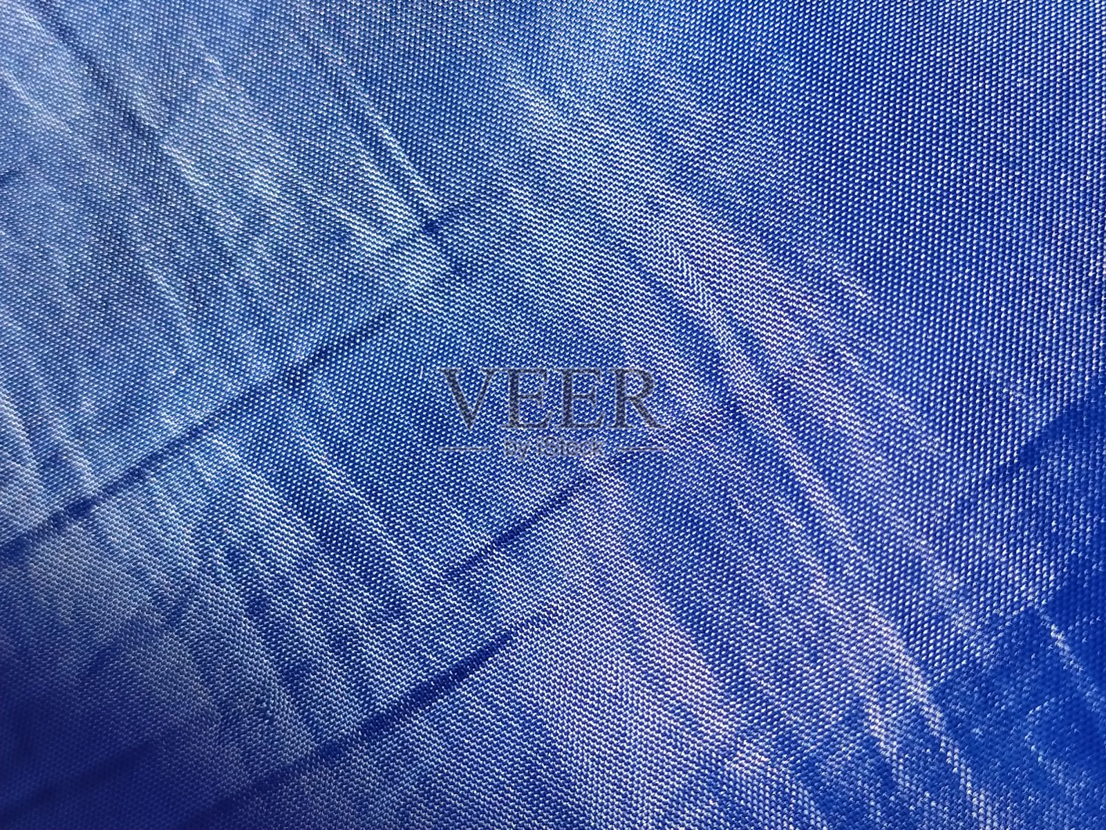 蓝色丝绸衬里。特写镜头。布窗帘或雨衣上的一块布抽象的宏观形象。编织薄线程照片摄影图片