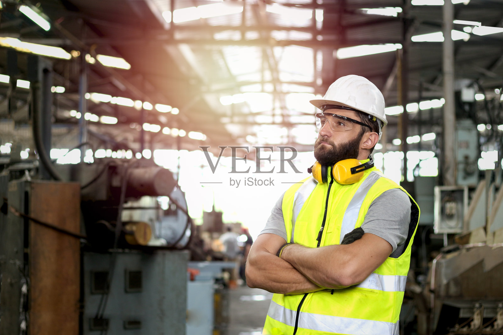 工业工程师工人的肖像戴着头盔和安全眼镜，双臂交叉站在制造工厂工业工厂照片摄影图片