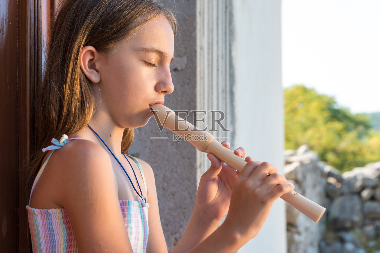 在古老的教堂门前，安详的女孩吹着木笛照片摄影图片