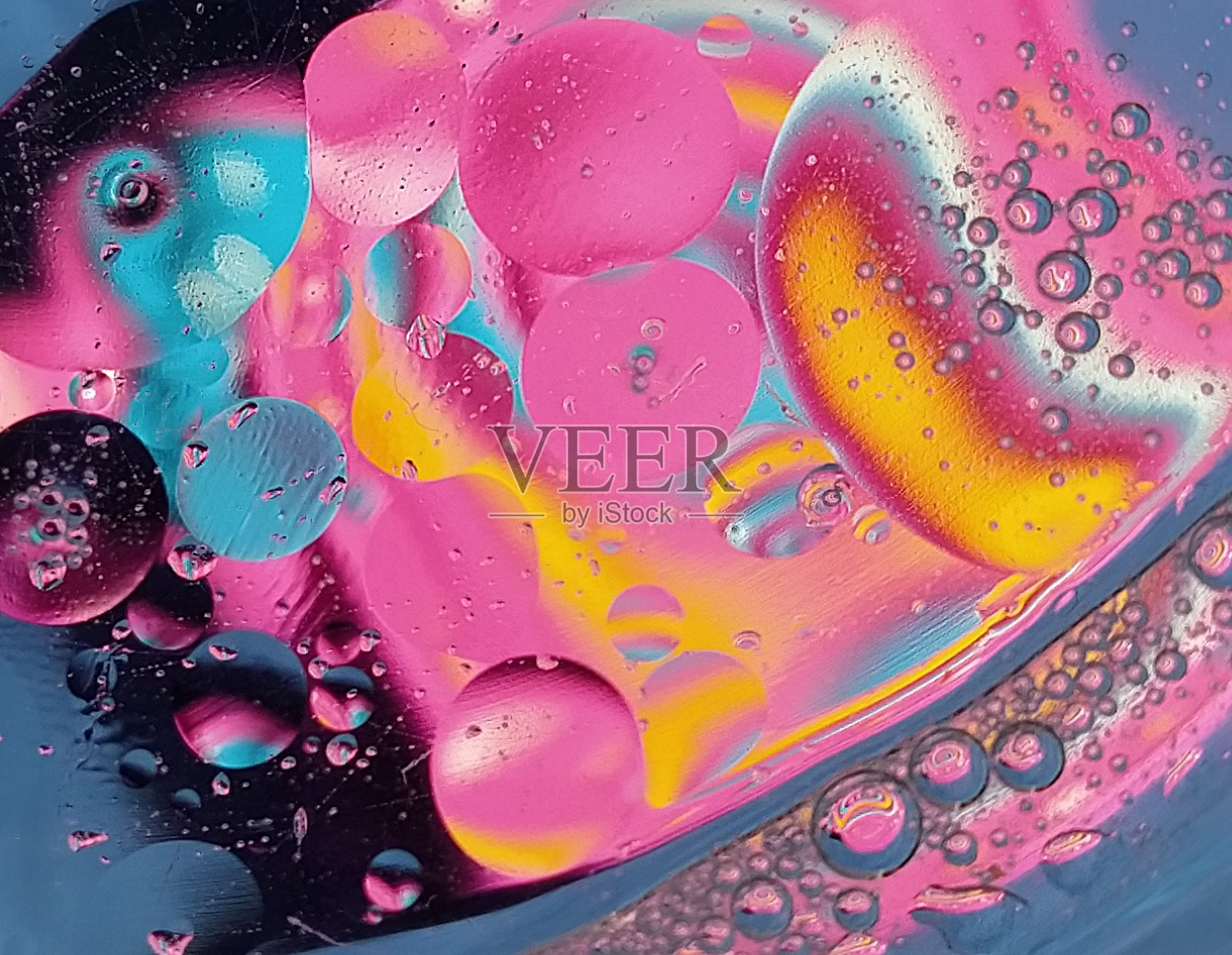 不同大小的圆形水滴的明亮背景。油滴在水中，颜色反射。对空间的抽象模仿。粉色、黄色和蓝色元素。圆圈和轮子。Macroabstraction照片摄影图片