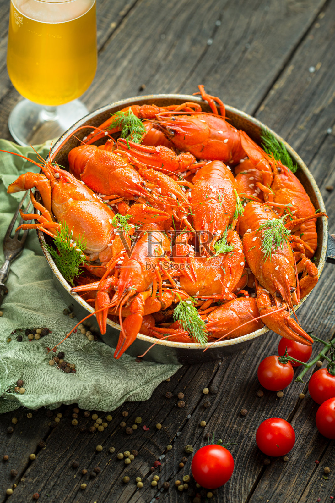 煮熟的小龙虾躺在一个质朴的煎锅里，在一个炖锅里，新鲜的香草，一杯啤酒，在黑色的背景上，还有酸橙和柠檬片照片摄影图片