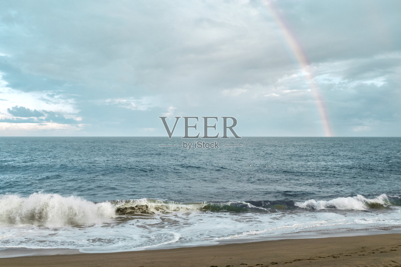 彩虹在海上。彩虹下的轻浪和沙滩照片摄影图片