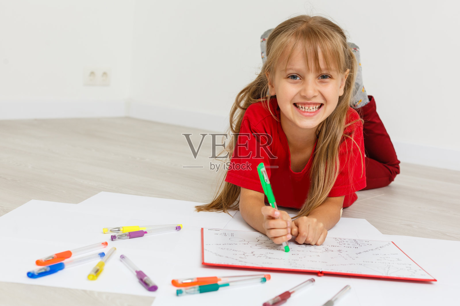 家庭教育概念-可爱的小女孩学习与成堆的书在家里的地板上。在白色背景上隔离照片摄影图片