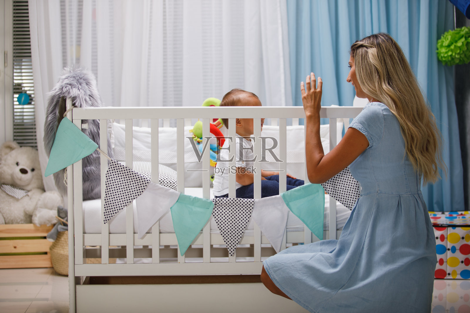 保护母亲跪在婴儿床前照片摄影图片