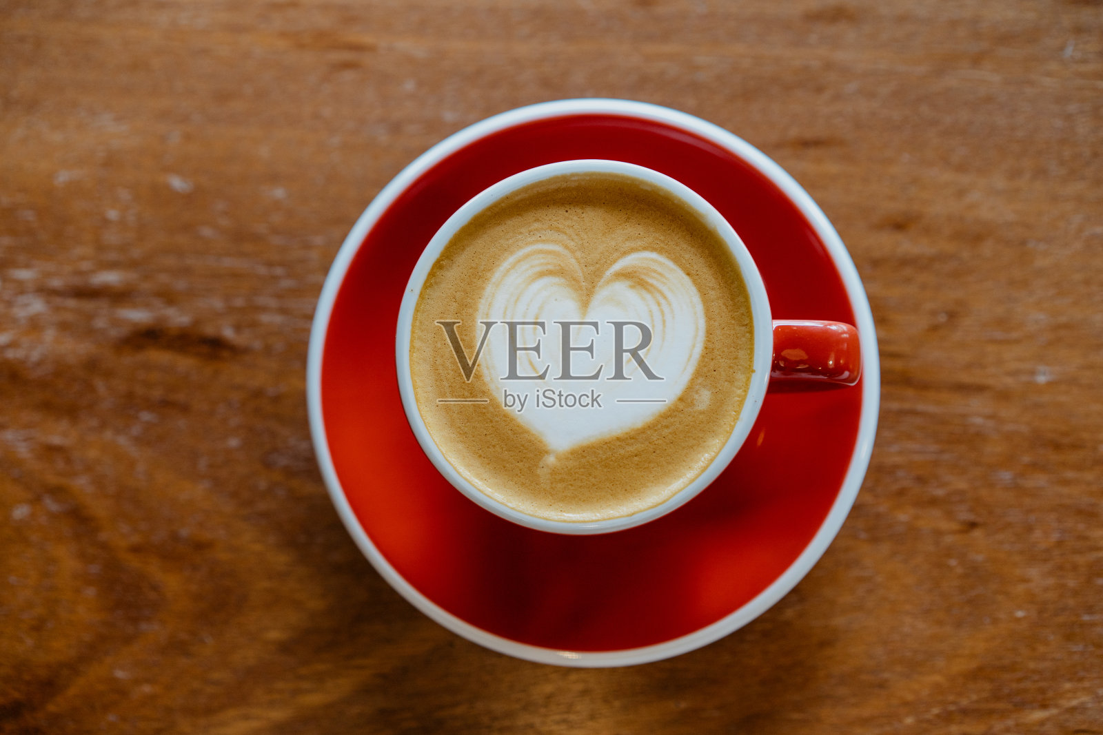 木桌上的红色咖啡杯上有泡沫的拿铁咖啡照片摄影图片