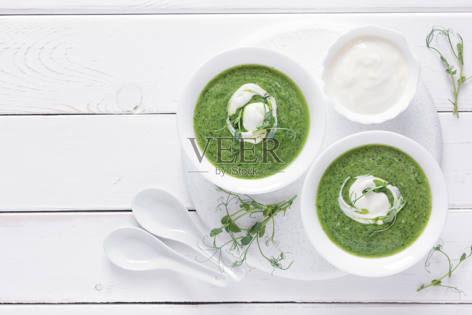 花椰菜和菠菜奶油汤，与微型绿色蔬菜在一个白色的碗在一个木制的桌子。健康饮食照片摄影图片