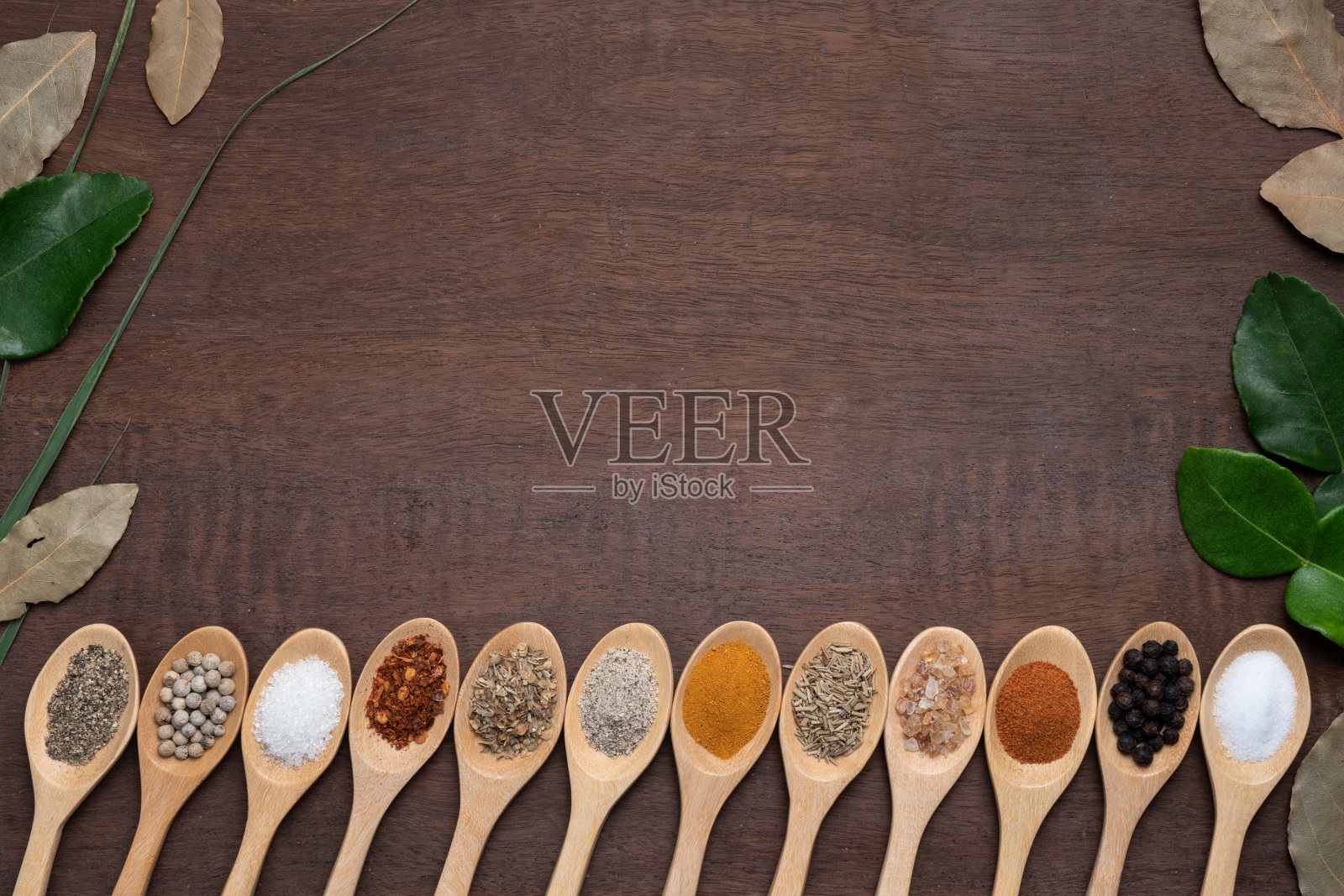 各种香料在木桌的木勺背景，糖，胡椒，盐，姜黄，迷迭香，牛至，拷贝空间照片摄影图片