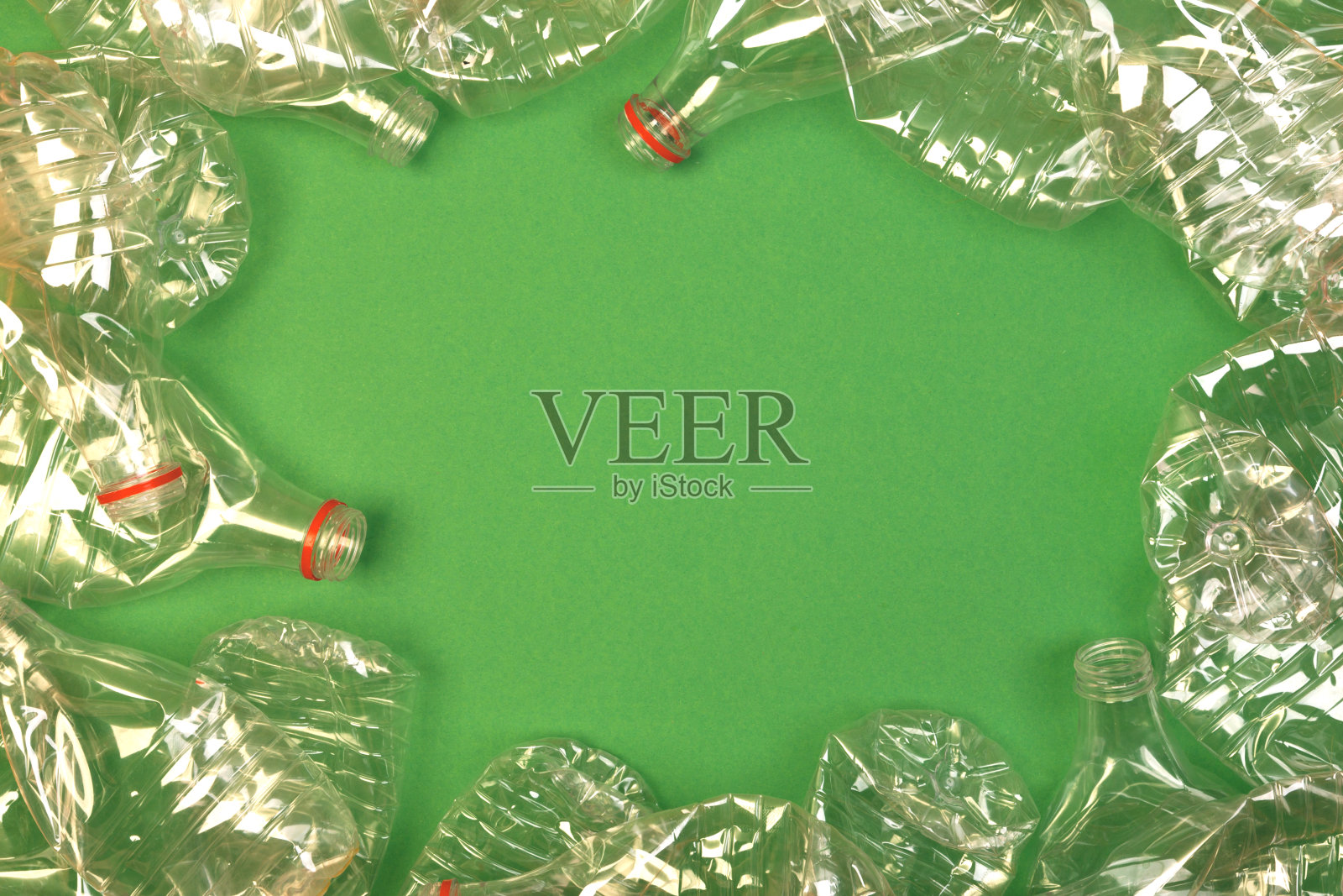 绿色背景上的皱巴巴的PET塑料瓶。照片摄影图片