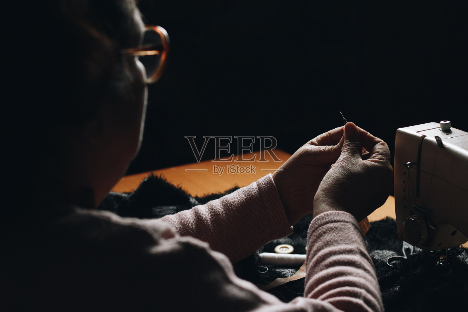 戴眼镜穿针的女裁缝照片摄影图片