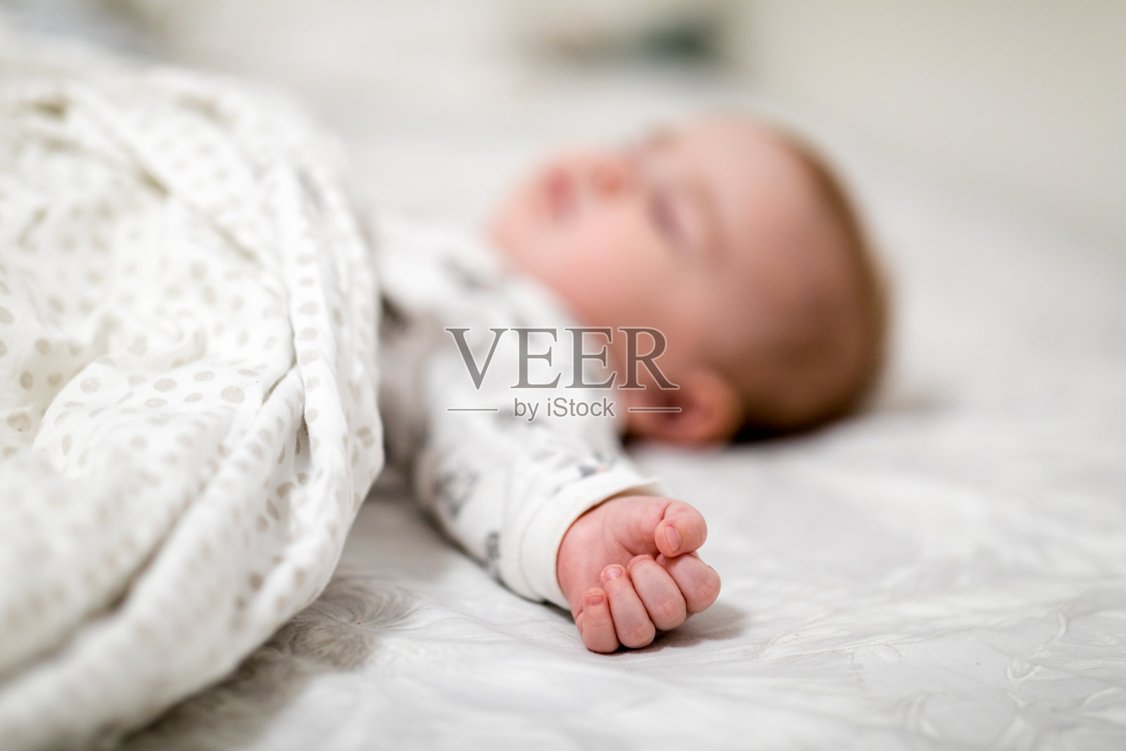 7个月大的宝宝睡在卧室的床上，拿着一个玩具照片摄影图片