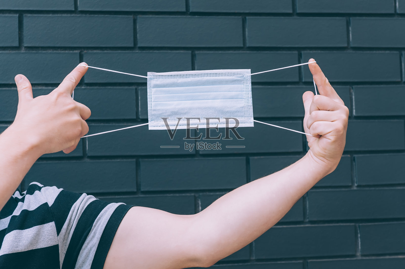 一个年轻人手里拿着医用口罩。2019冠状病毒病防护与预防。照片摄影图片