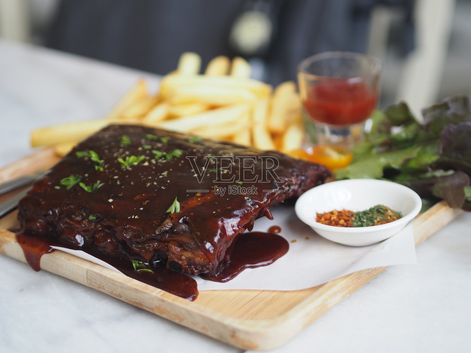 食物排骨配烧烤酱烤，蜂蜜加焦糖，配法式炸薯条，放在木盘上照片摄影图片