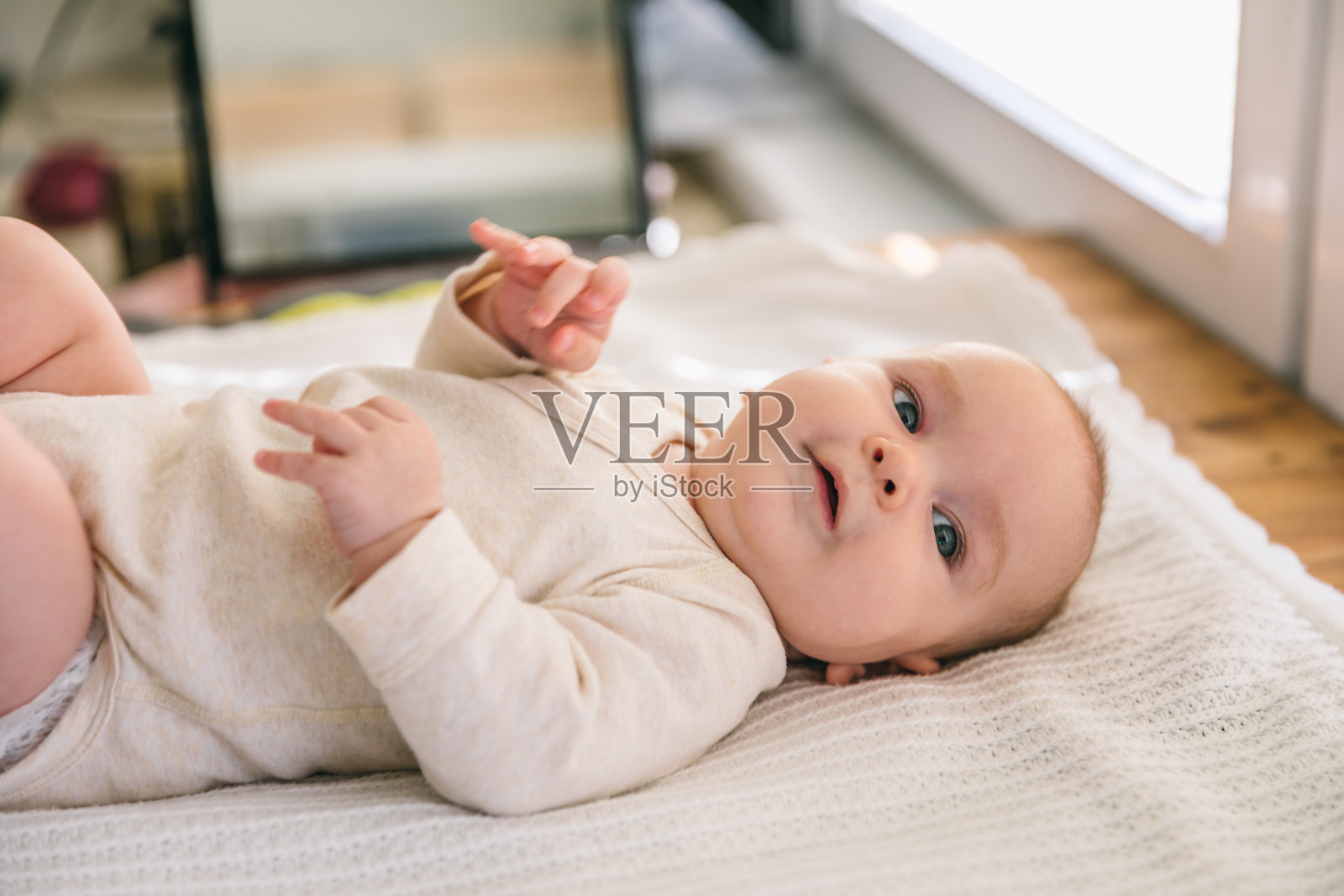 两个月大的新生儿微笑着躺在白色的毯子上。心理运动发育和婴儿护理照片摄影图片
