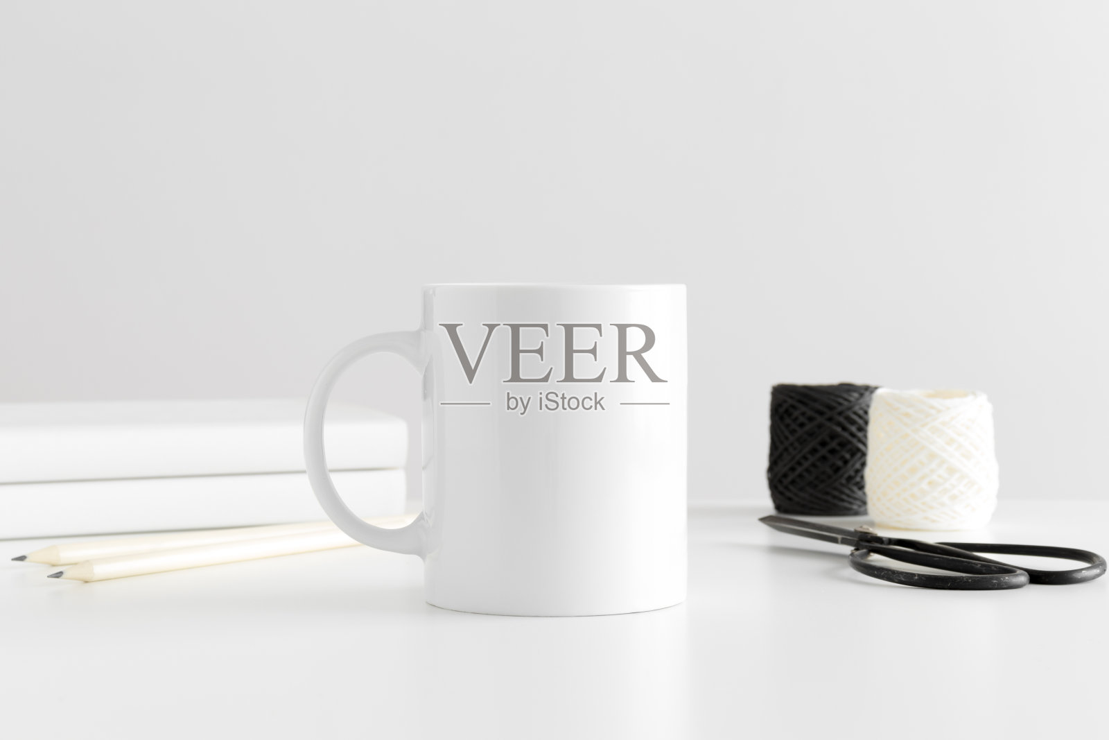白色桌子上的马克杯模型和工作配件。照片摄影图片