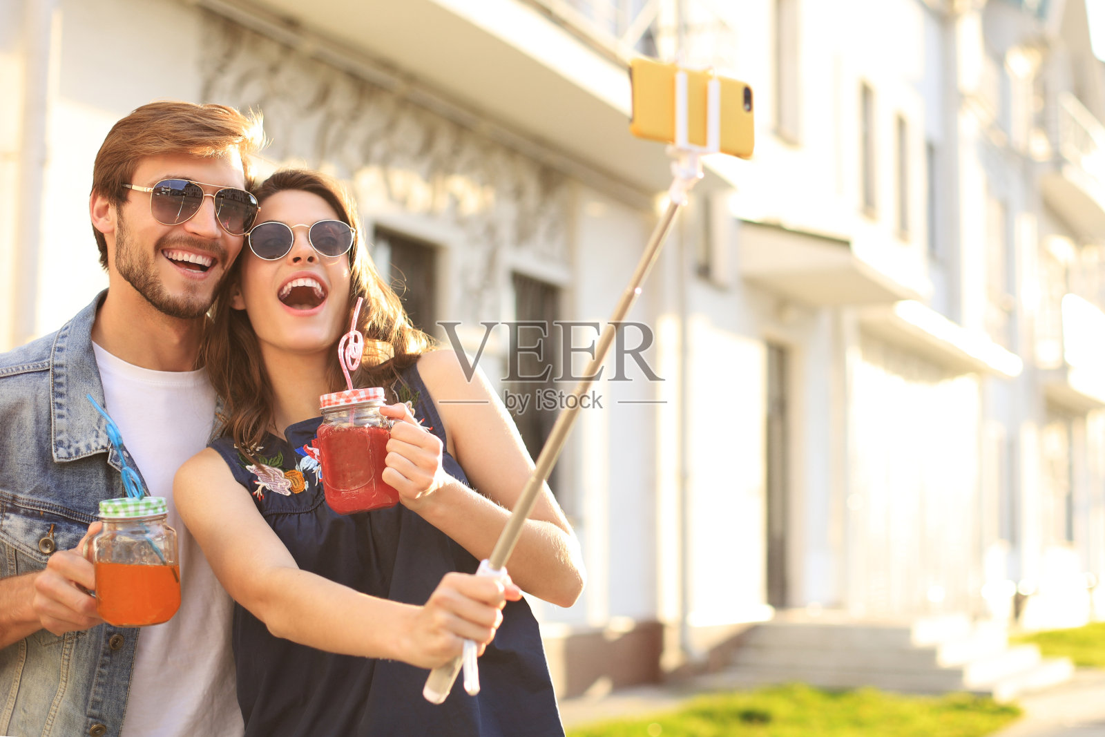 一对美丽可爱的年轻夫妇走在城市的街道上，拥抱着自拍。照片摄影图片