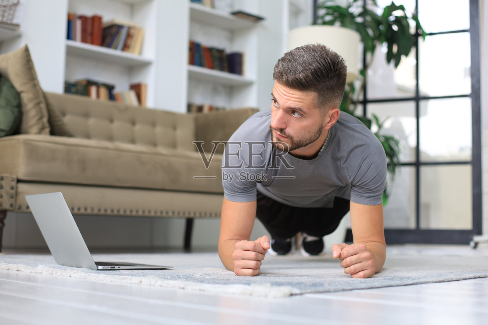 英俊的大汉在家里做平板支撑运动。健身是健康的关键。照片摄影图片