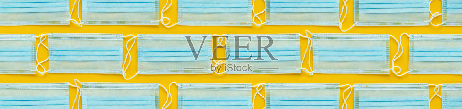 黄色背景上的一次性医用口罩布局。个人防护装备，PPE。照片摄影图片