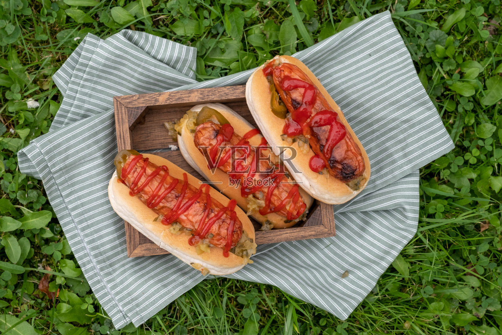 野餐桌上的烤热狗配番茄酱和佐料照片摄影图片