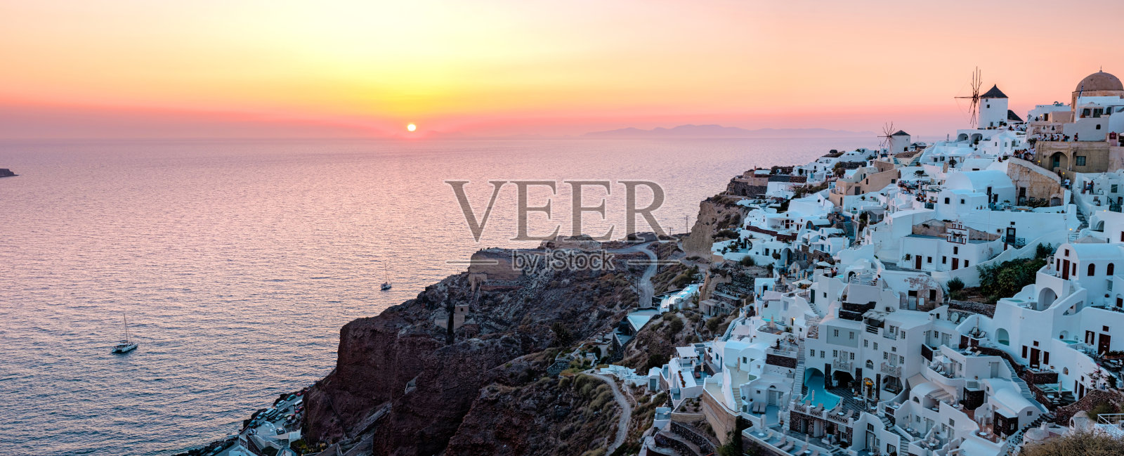 日落在希腊圣托里尼岛，美丽的白色村庄伊亚与教堂和风车日落照片摄影图片