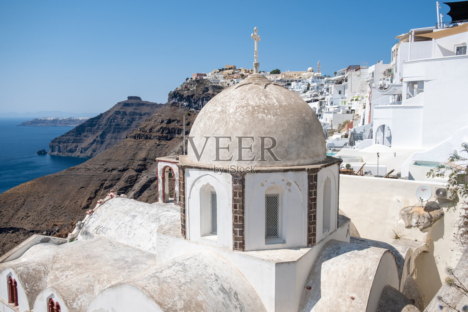 白色教堂在费拉圣托里尼，从费拉镇，希腊圣托里尼岛的全景山，海和自然。火山口和海湾里的船只照片摄影图片