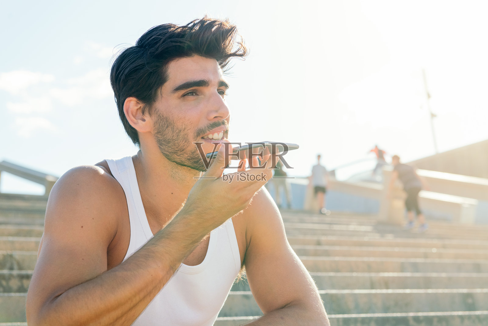 穿着背心的运动男在录语音信息照片摄影图片