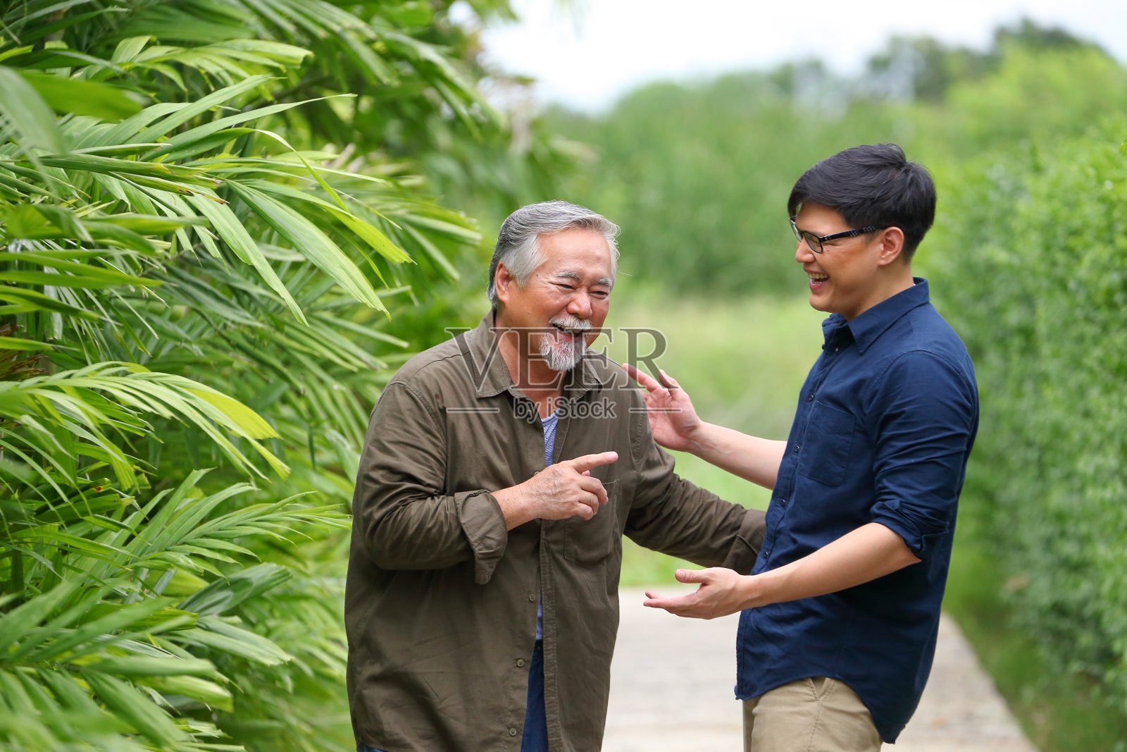 年长的亚洲男人和他的儿子大声笑着，谈论他们作为父亲和儿子一起分享的有趣的记忆照片摄影图片
