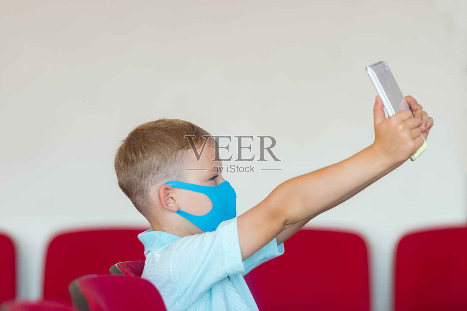 一个戴着蓝色口罩的学生正在上课。大流行期间安全返回学校的概念。保持社交距离以抗击COVID-19照片摄影图片