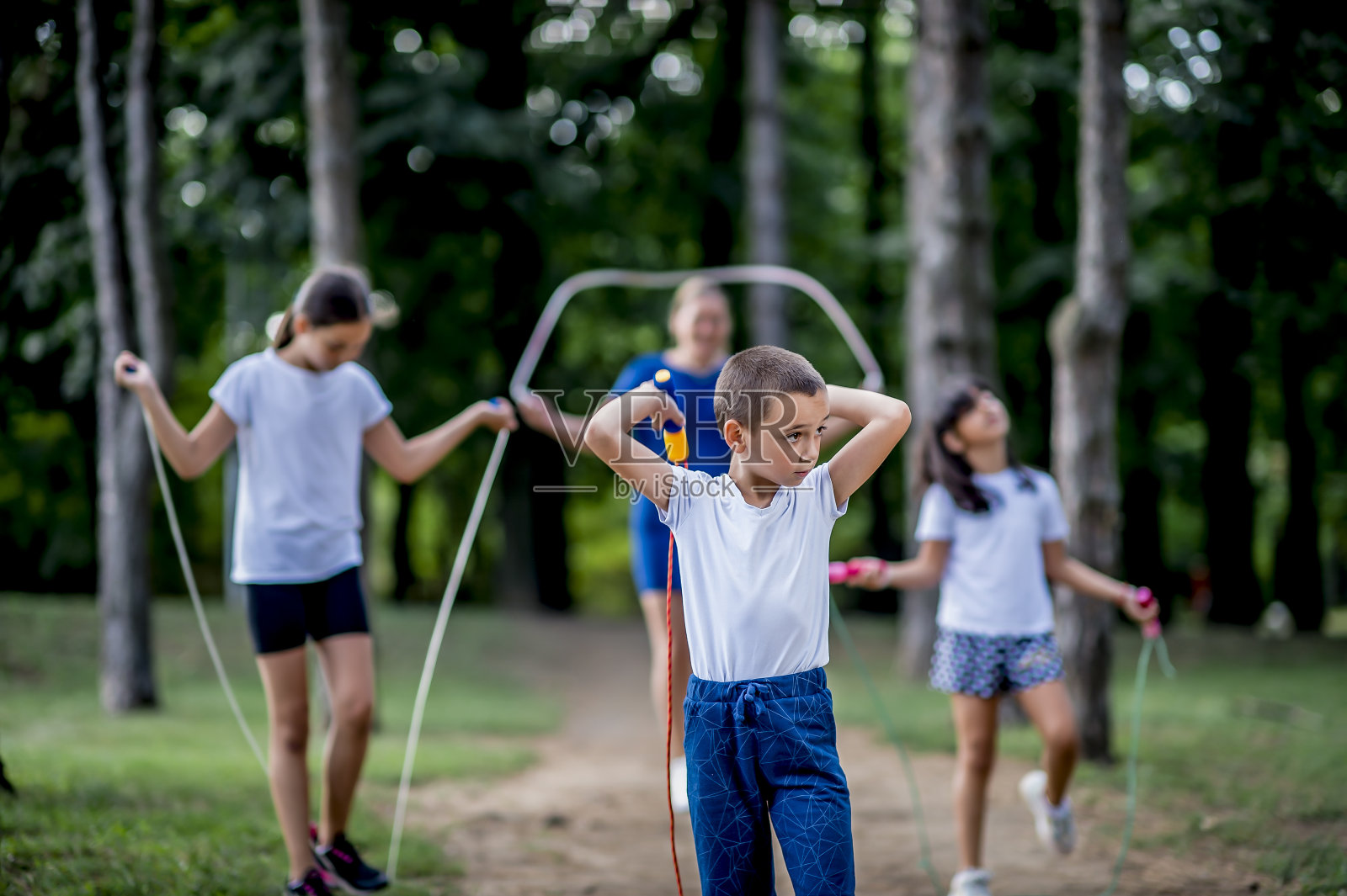 穿着白色t恤的学生在公园里跳绳照片摄影图片