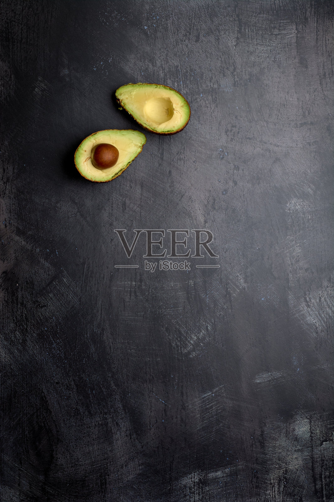 一组切割和未切割的牛油果，在一个黑暗，黑色，水泥，金属，大理石和石头的背景照片摄影图片