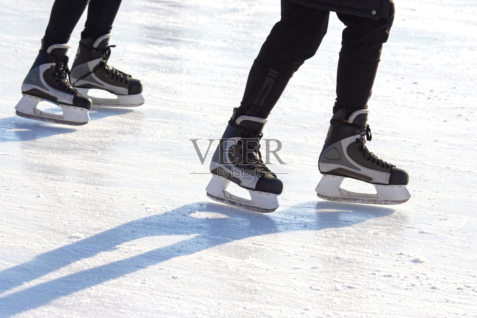 在溜冰场上滑冰的人的腿。业余爱好和体育。假期及冬季活动照片摄影图片