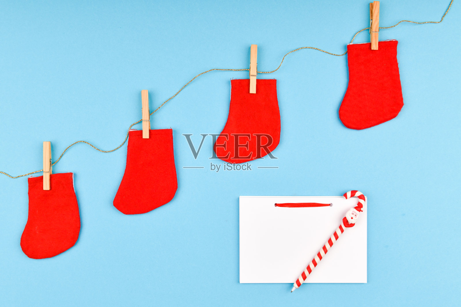 晒衣夹上的红袜子。在蓝色背景上。一个空白的笔记本和一堆。从以上观点。在蓝色背景上用晒衣夹挂在晒衣绳上。新年的概念照片摄影图片
