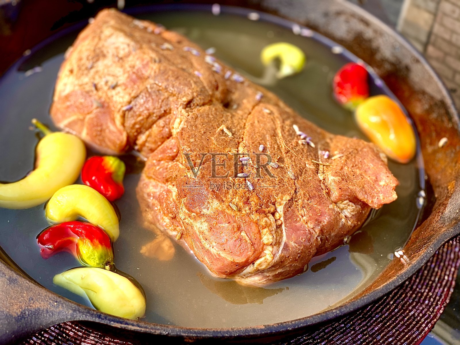 用药草和香料擦过的猪屁股与啤酒和辣椒一起放在铸铁锅里，准备进行12小时的硬木材熏制过程照片摄影图片