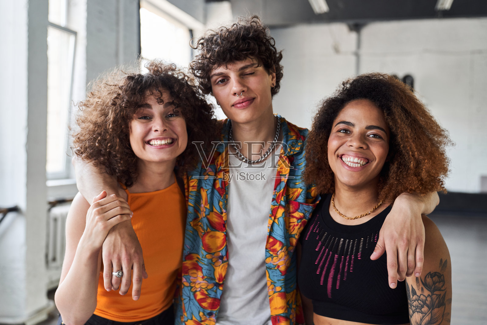 卷毛男拥抱他的两个女性朋友照片摄影图片