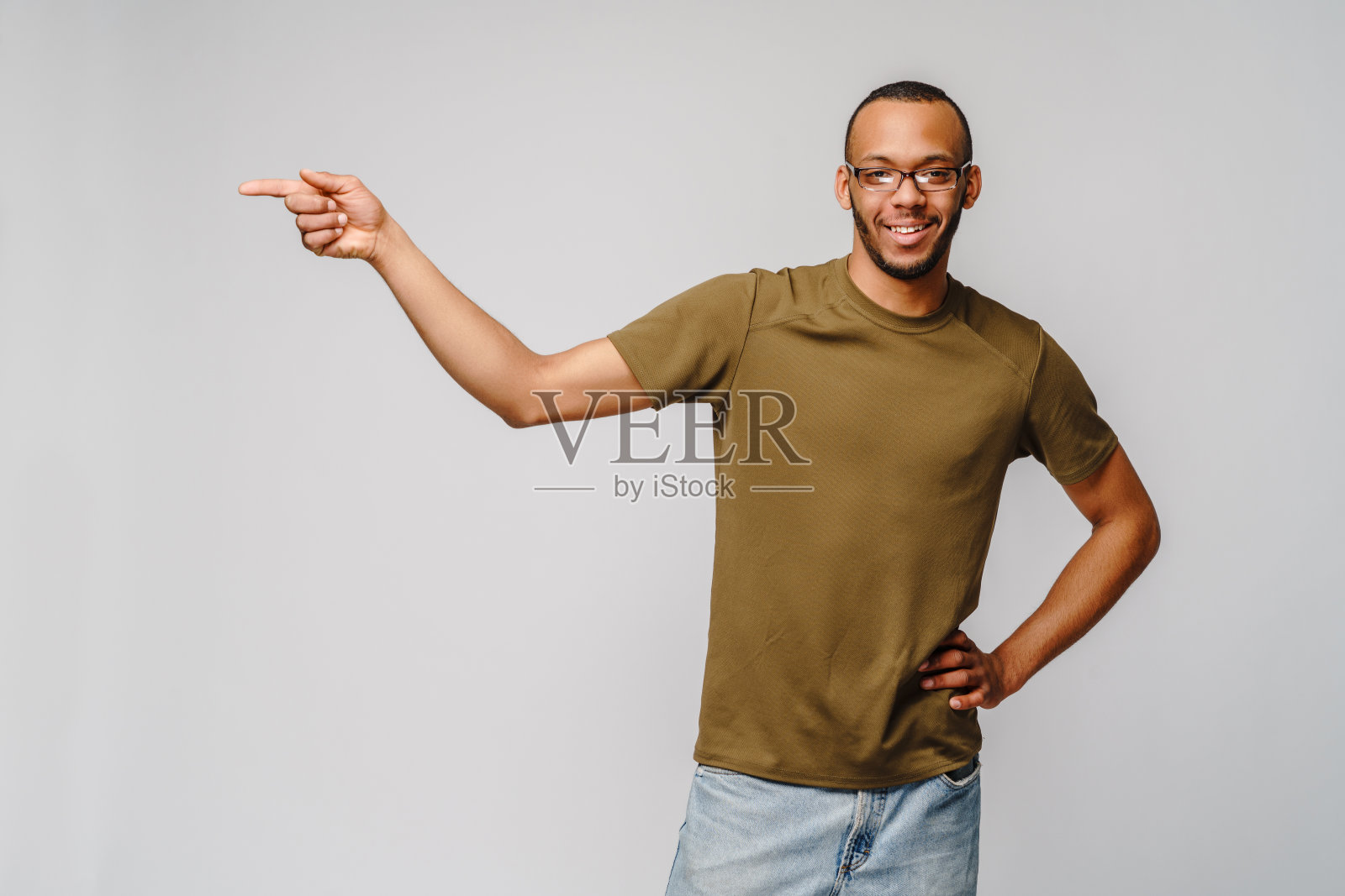 快乐友好的非洲裔美国青年穿着绿色t恤指着拷贝空间照片摄影图片