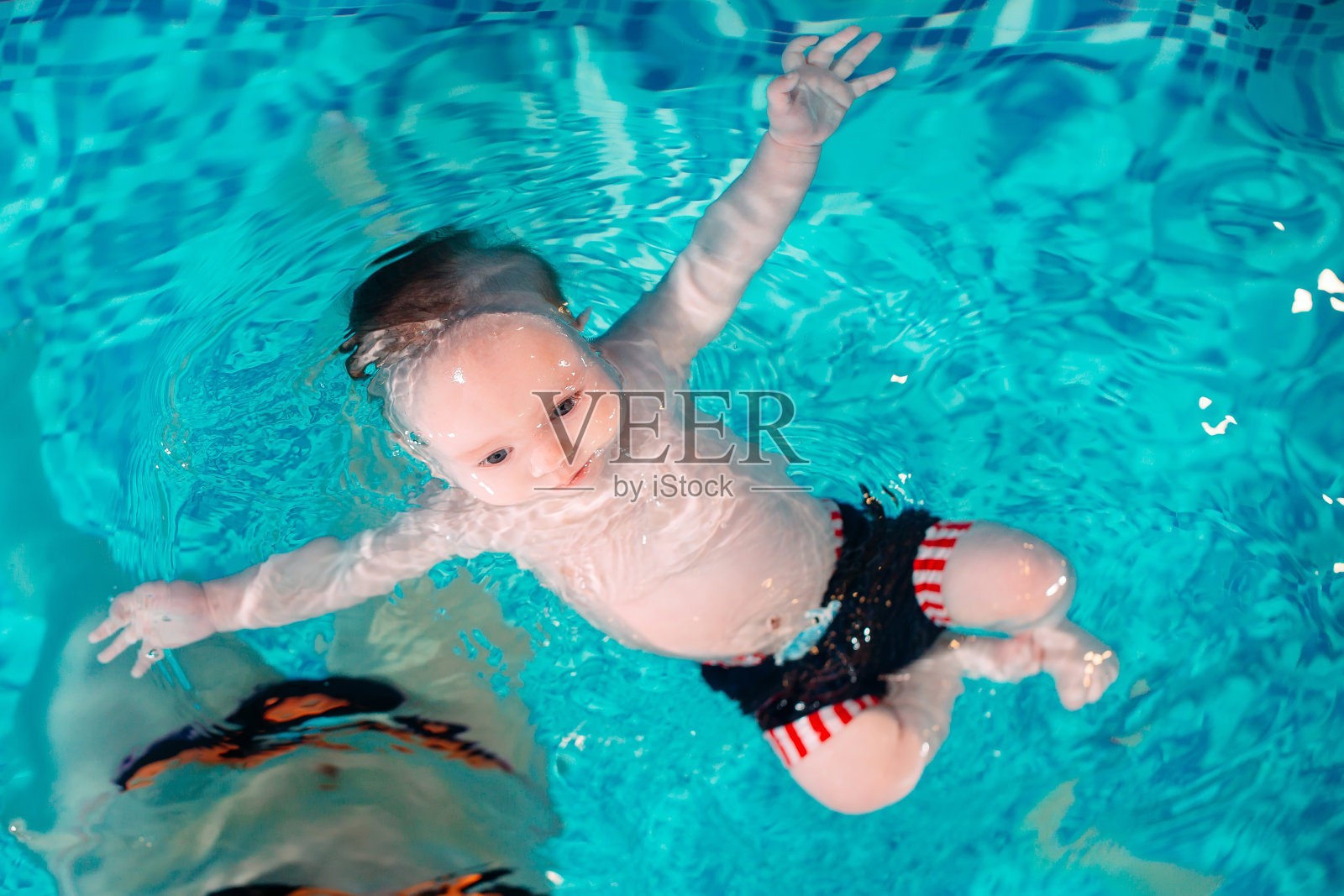 一群妈妈和她们的孩子在一个有教练的儿童游泳班。照片摄影图片