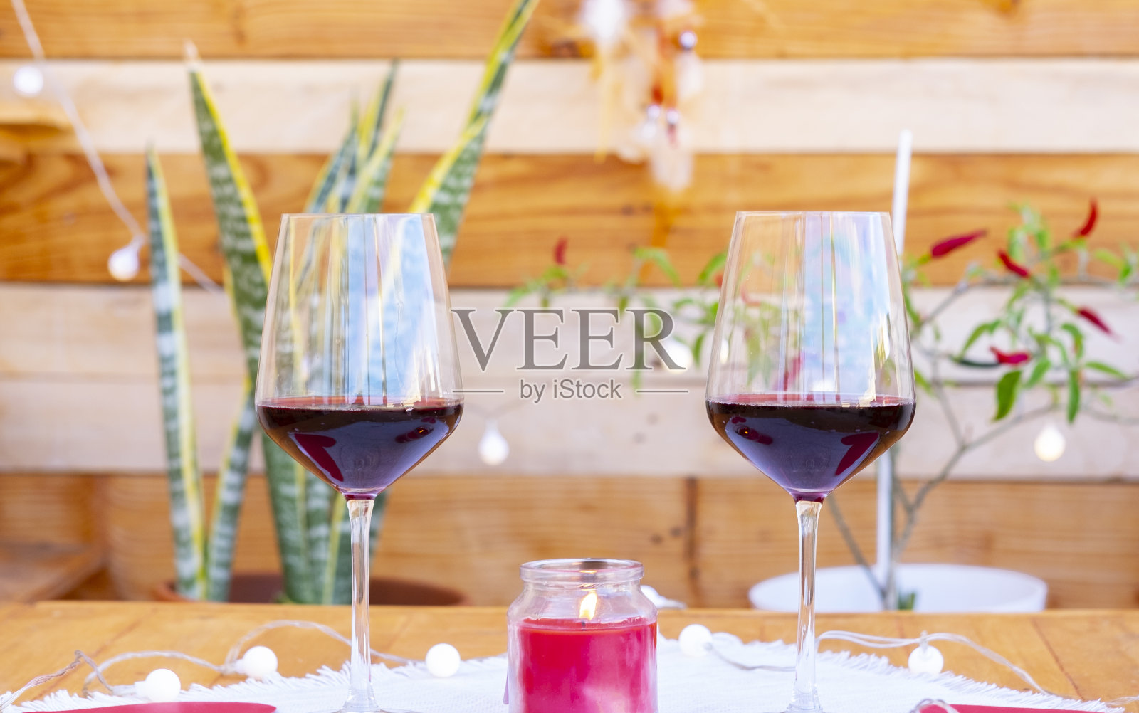 木制的桌子，两个红酒杯，等待相爱的情侣。浪漫的木质背景，植物，蜡烛和灯光照片摄影图片