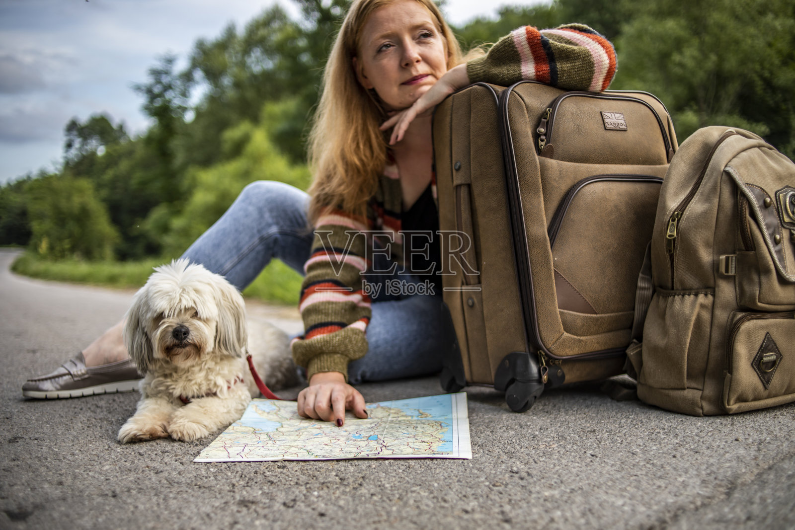 一个小女孩坐在一个手提箱旁边，抚摸着她的狗照片摄影图片