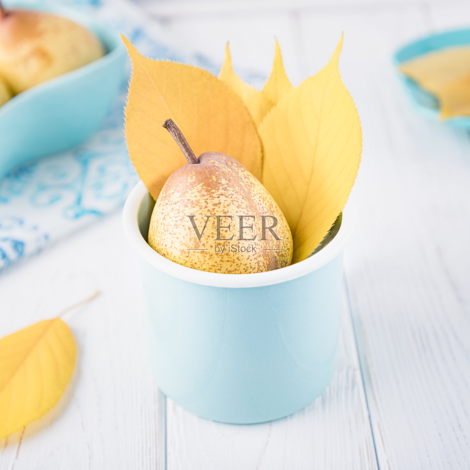 新鲜成熟的梨子和黄色的秋叶在搪瓷杯在白色的背景。健美的照片。本空间照片摄影图片