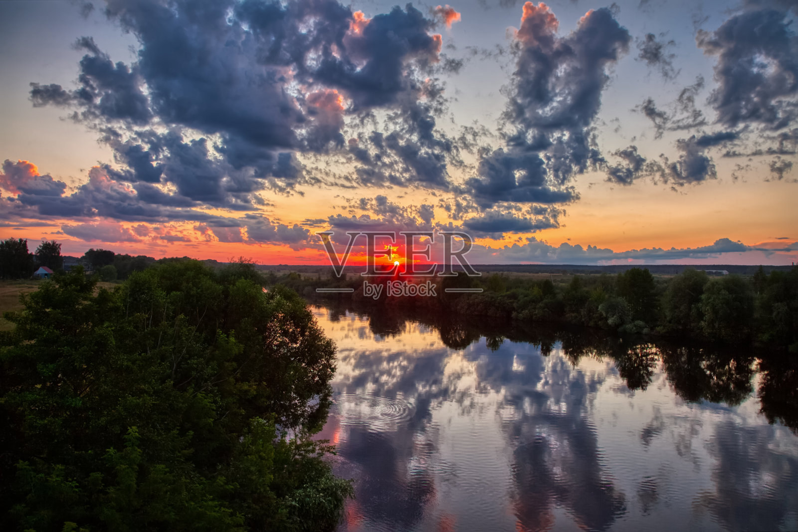 美丽的夏日日落在黄昏的天空上的河。夕阳下的天空在河水里的倒影。太阳藏在地平线后面了。照片摄影图片