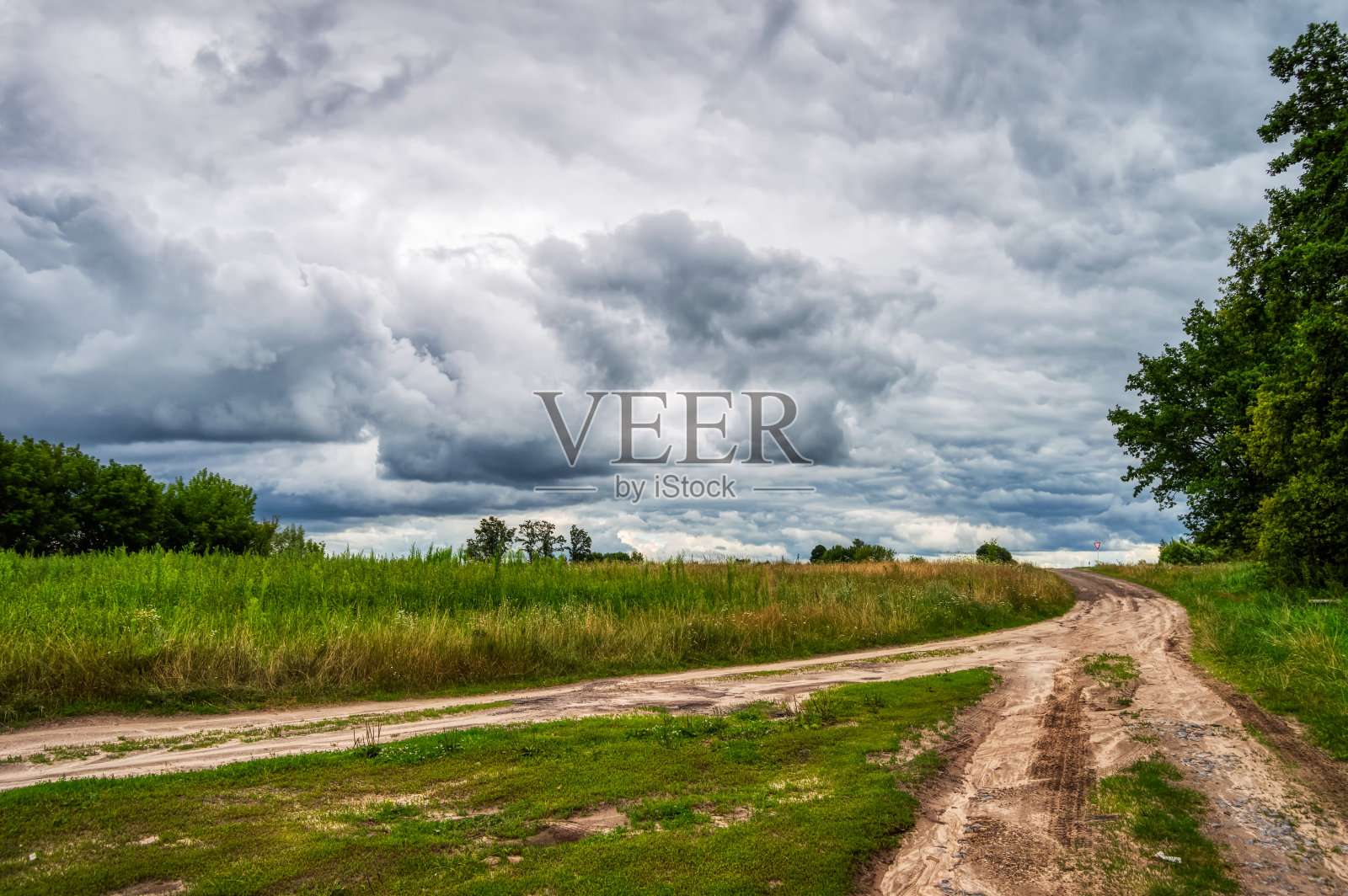 带有狭窄乡村道路的乡村景观。在夏天暴风雨的天空下，道路越过了地平线照片摄影图片