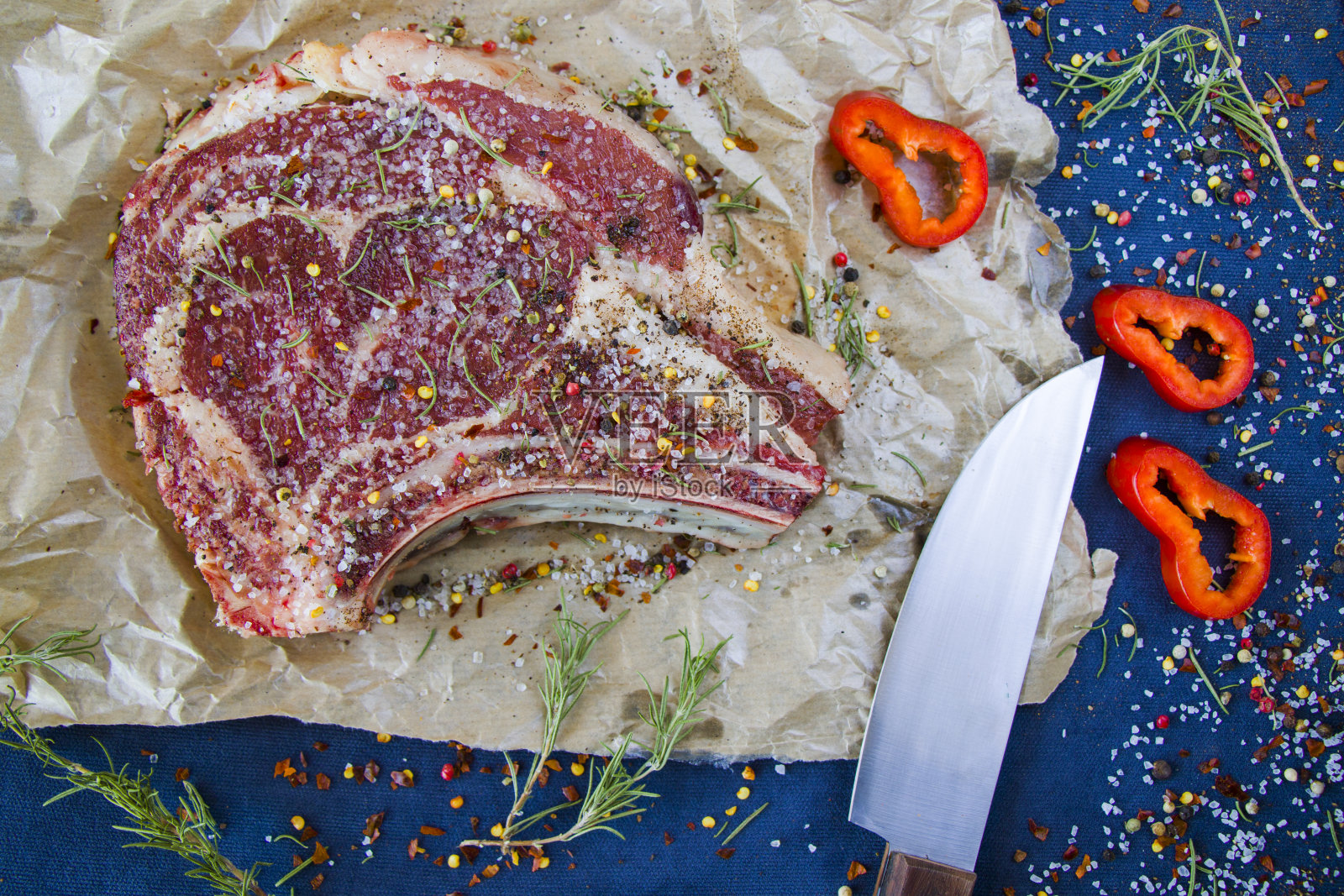 餐桌上的生牛肉、香料和迷迭香、肋眼牛排的配料。胡椒和粗盐。照片摄影图片