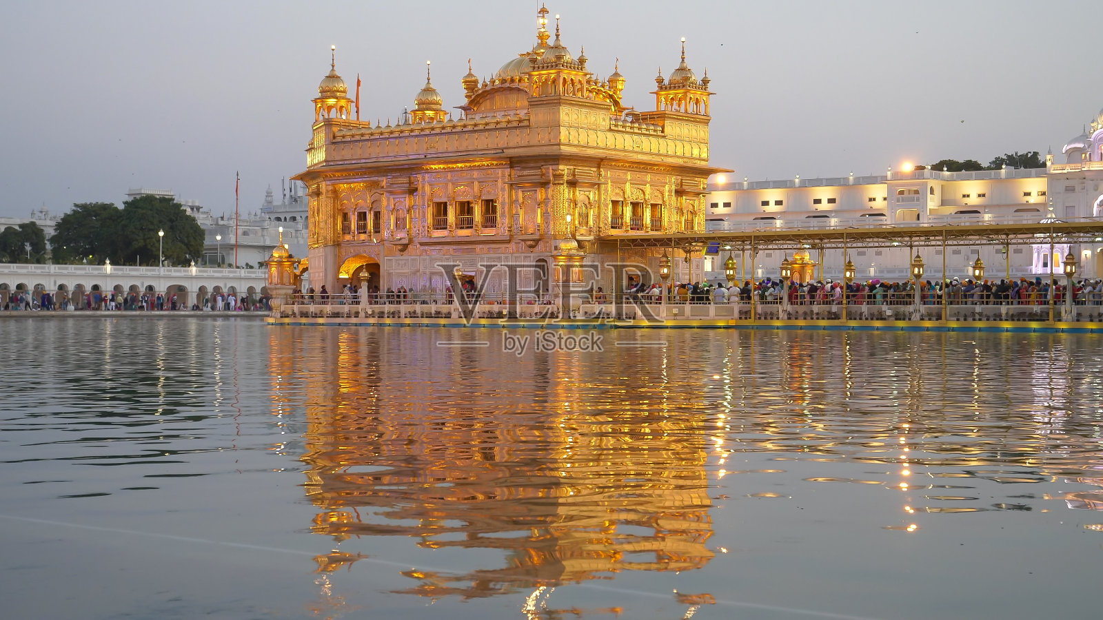 日落时拍摄的金色寺庙及其在阿姆利则的倒影照片摄影图片