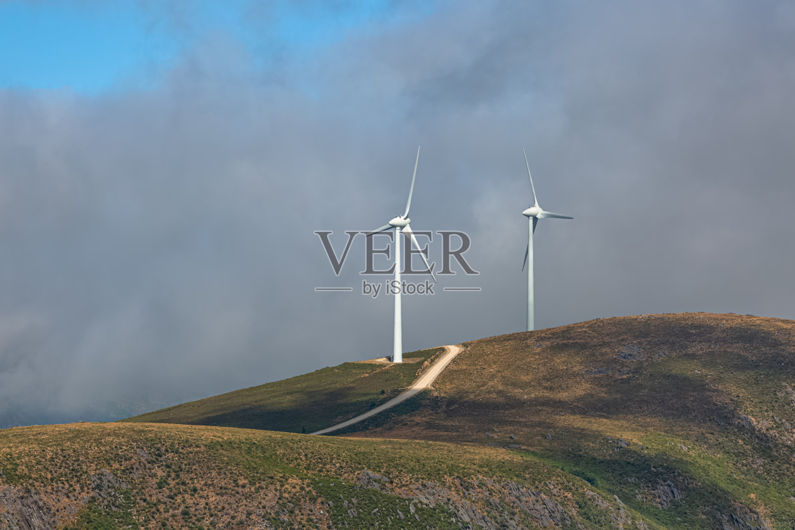 山顶上的风力涡轮机，多云的天空和雾作为背景照片摄影图片