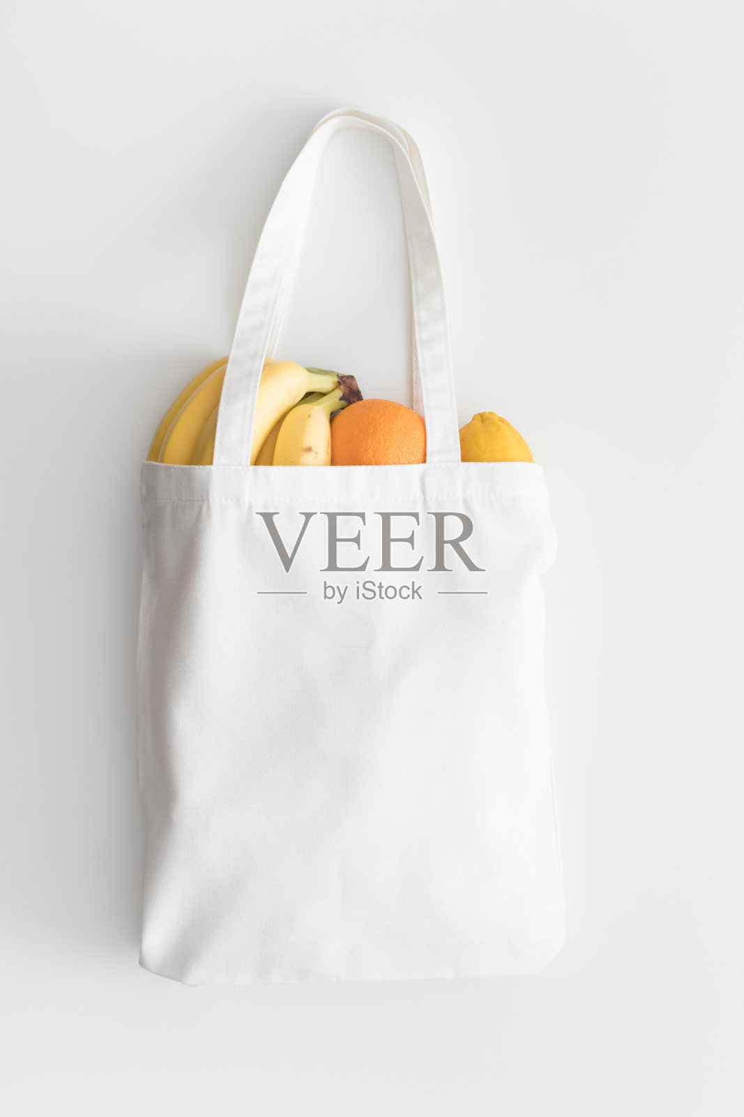 白色大手提袋模型与水果在白色桌子上。照片摄影图片