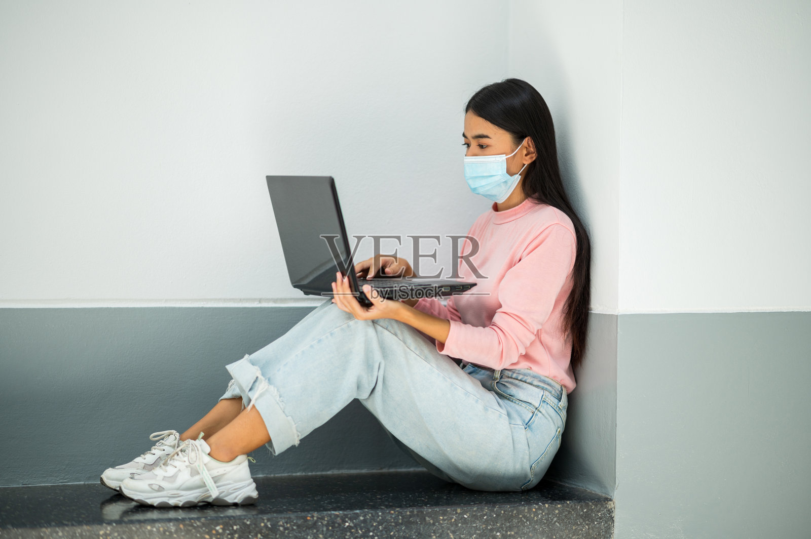 一位拿着笔记本电脑的女学生坐在大学里照片摄影图片