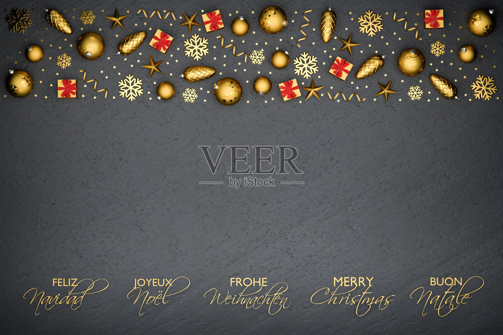 把金色的圣诞装饰品平放在一个黑色的石盘上。下面用西班牙语、法语、德语、英语和意大利语写“圣诞快乐”。照片摄影图片