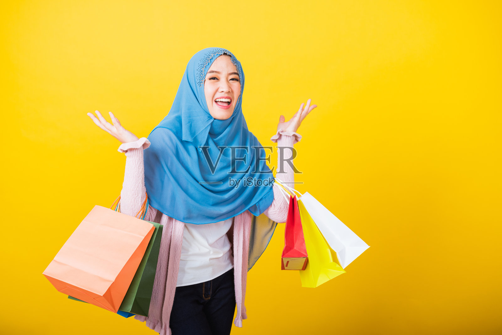 亚洲穆斯林阿拉伯妇女伊斯兰戴着头巾，她拿着五颜六色的购物袋如此高兴照片摄影图片
