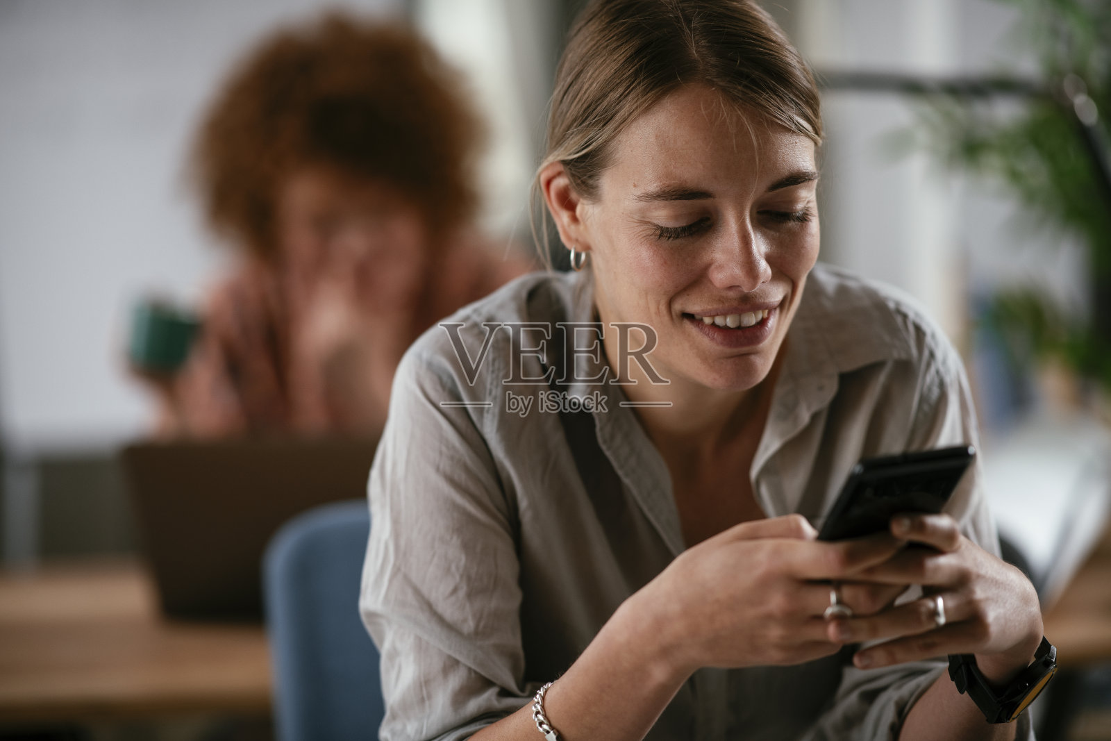 年轻的女商人在办公室里打电话。照片摄影图片