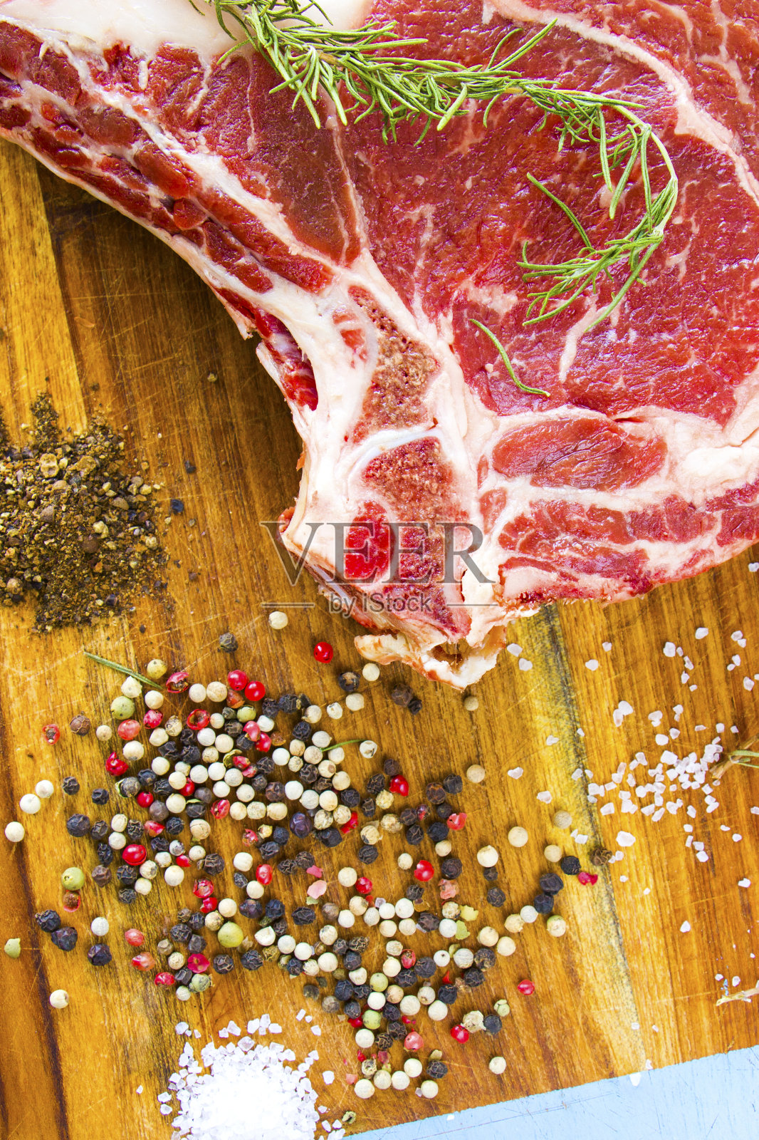餐桌上的生牛肉、香料和迷迭香、肋眼牛排的配料。胡椒和粗盐照片摄影图片